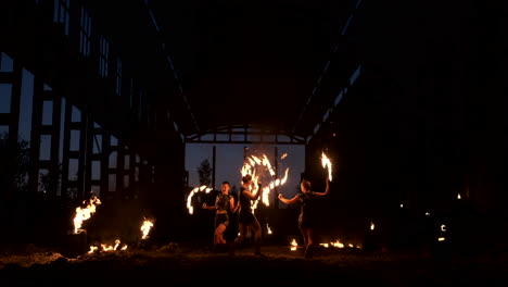 Eine-Gruppe-Von-Menschen-Mit-Feuer-Und-Fackeln-Tanzt-Bei-Sonnenuntergang-Im-Hangar-In-Zeitlupe.-Feuershow.